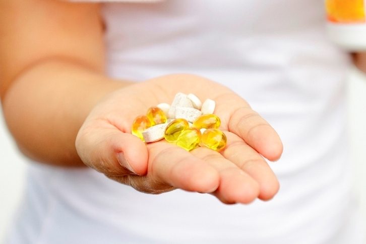 sport and diet concept - woman hand with vitamins and medication